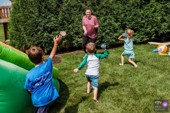 Moment-driven San Francisco backyard family photography in the backyard during a water balloon fight