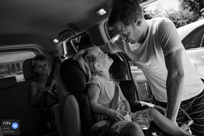 Moment-driven SF, CA family photography with dad helping with getting buckled in