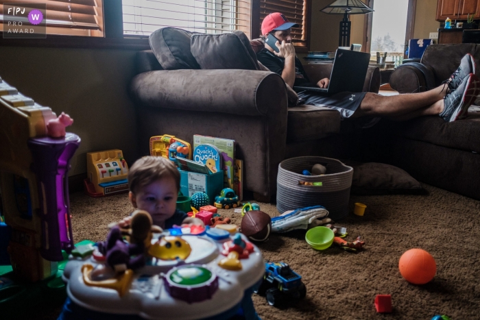 Momentangetriebenes San Francisco Familienfotojournalismusbild von Vater und Kind, die im Wohnzimmer beschäftigt sind