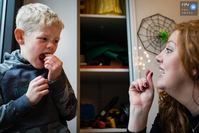 Moment driven Cambridgeshire family photojournalism image showing Mum helps son who has a lose tooth and looks anxious, by suggesting he twist it