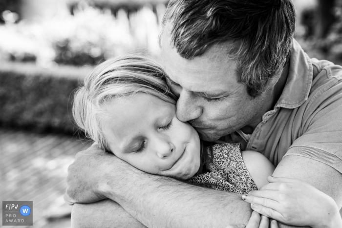 Moment-driven Flanders family photography of a dad kiss during BW day in the life session