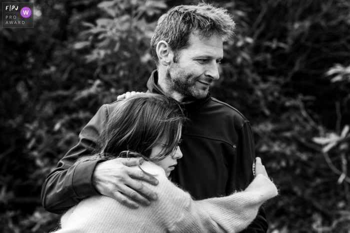 Image de photojournalisme familial de Flandre animée par un moment montrant un câlin pour papa pendant la journée dans la session de vie en BW