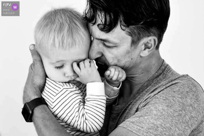 Moment-driven Belgium family photography with father holding toddler in BW Moment-driven Belgium family photography with father holding toddler in BW