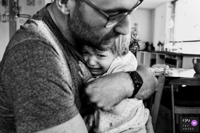 Moment-driven East Flanders family photography with dad and child hugging during a day in the life photo session