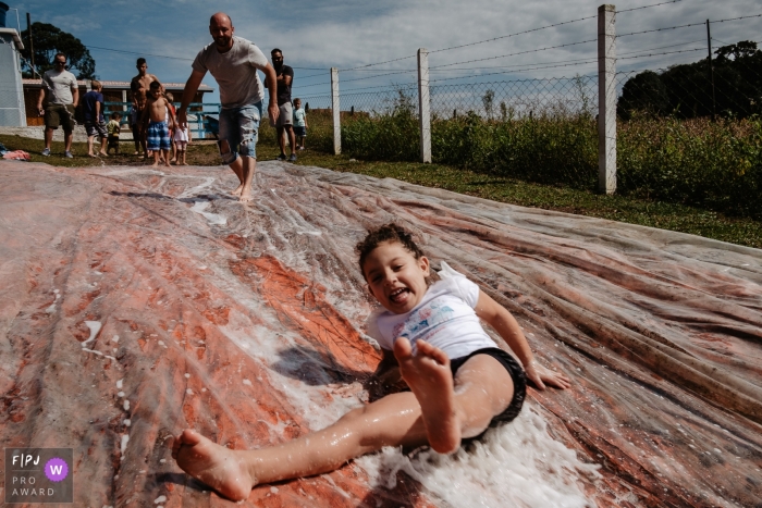 Image de photojournalisme de la famille Santa Catarina animée par un moment d'une fille glissant et jouant le jour de son anniversaire