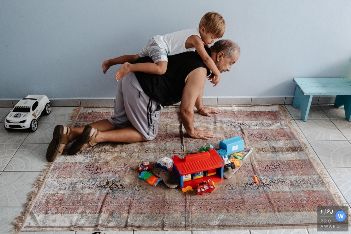 Moment-driven Florianopolis family photography of a Grandfather playing with his grandson who climbs on his back