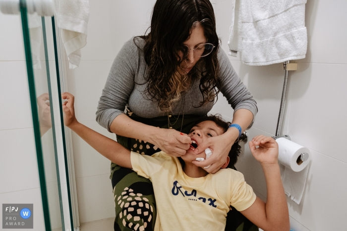 L'image du photojournalisme familial de Florianopolis, animée par un moment, a capturé la mère se brossant les dents et passant la soie dentaire à son fils avant de se coucher dans la salle de bain à la maison