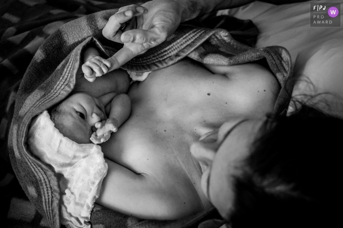 Hospital Sepaco birth photography capturing a baby looking at his mother while holding his father's finger Hospital Sepaco birth photography capturing a baby looking at his mother while holding his father's finger