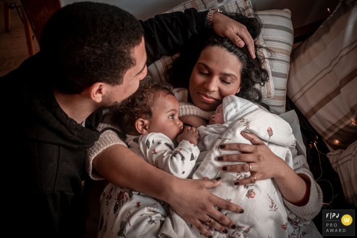 Mother with the child who has just been born in a home birth, breastfeeding her firstborn Sao Paulo at-home birth image showing skin-to-skin mother with the child who has just been born in a home birth, breastfeeding her firstborn and being supported by her partner