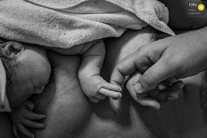 Photographe de naissance à Rio de Janeiro d'un moment mignon et affectueux juste après la naissance. Bébé vient de naître tenant le doigt de son père. Le lien du bébé avec ses parents est instantané