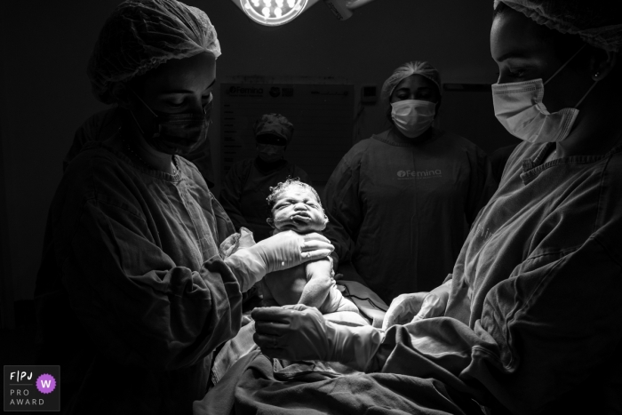 Maternidade Femina birthing photo of a newborn being lifted out of the mother during a c-section