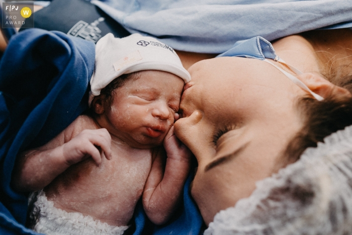 Santa Catarina mother kisses her newly born child at this Maternidade Santa Helena photography coverage