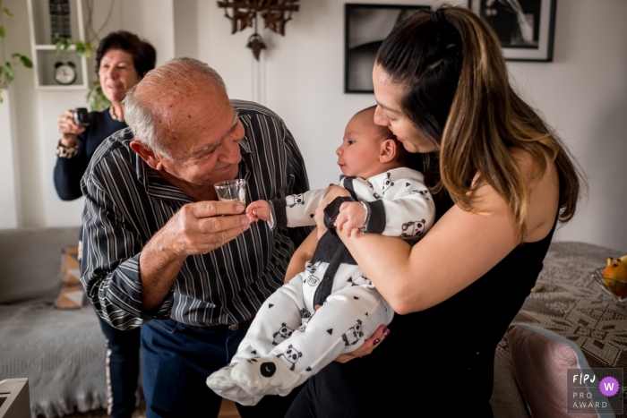 Die Großeltern von Sao Paulo sind alle glücklich, während sie während dieser Familienfotografie-Sitzung ein unangemessenes Getränk für das Baby anbieten