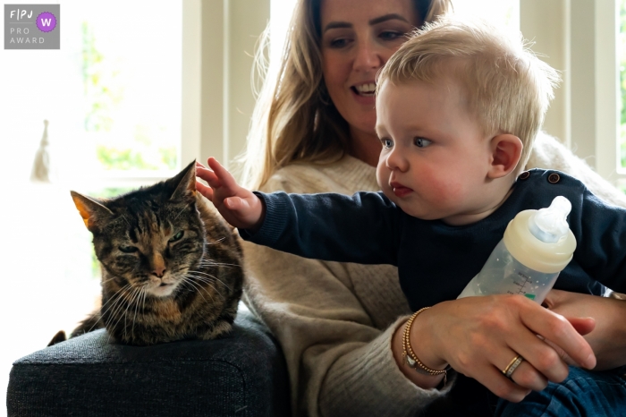 Zuid Holland photo de famille d'un jeune garçon prenant une pause de sa bouteille pour tendre la main à son chat