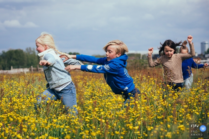 Amsterdam children playing catch in a spring flower field during a family photo session