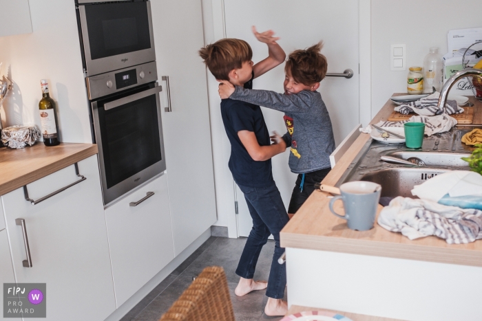 Two brothers fighting in the kitchen captured by Antwerpen photographer during a family session Two brothers fighting in the kitchen captured by Antwerpen photographer during a family session