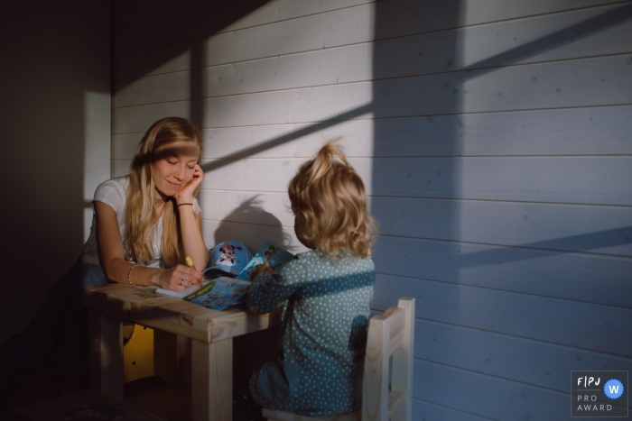 Tallinn-Fotoshooting zu Hause mit einer Mutter und einer Tochter, die sich ein Buch anschauen