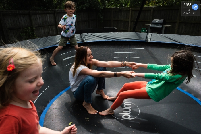 Cambridgeshire Familien- und Kinderfotografie einer Mutter, die mit ihren Kindern auf dem Trampolin spielt