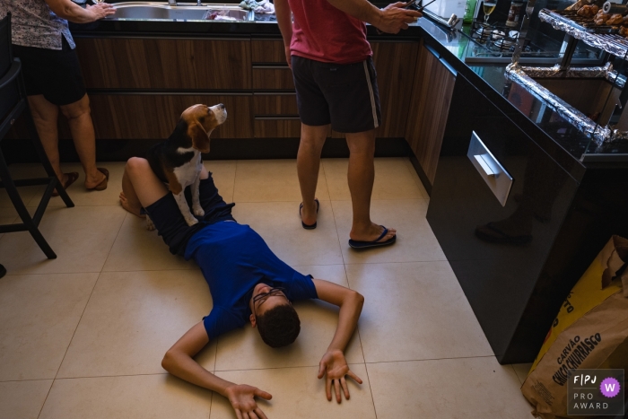 Cuiaba day in the life session with a family working in the kitchen and a dog siting on a boy laying on the floor Cuiaba day in the life session with a family working in the kitchen and a dog siting on a boy laying on the floor