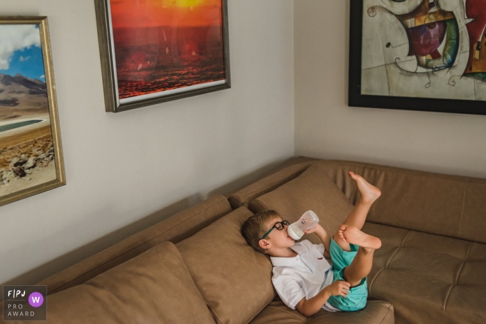 Campo Grande family photography coverage of boy enjoying the baby bottle on the sofa 