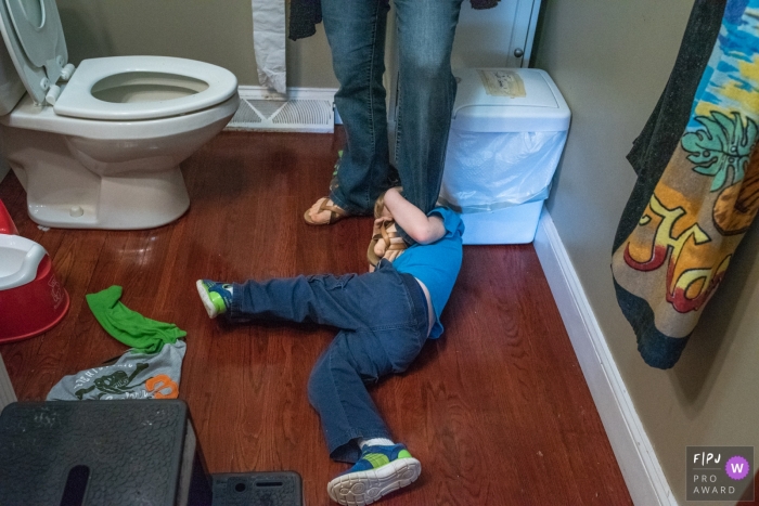 Connecticut family image of a young boy struggling with his mother as he lays on the floor in the bathroom Connecticut family image of a young boy struggling with his mother as he lays on the floor in the bathroom