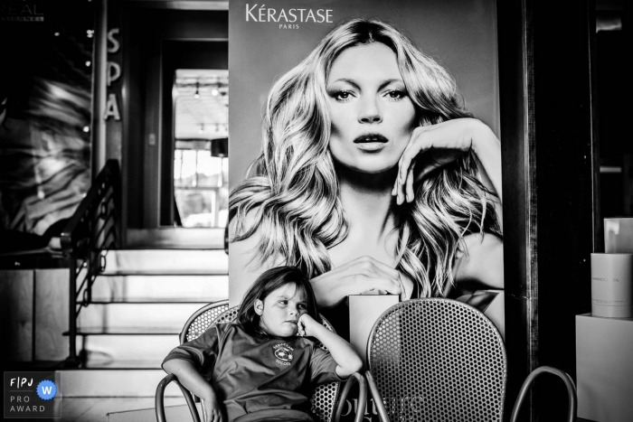 New Hampshire family photography displaying a little girl sitting below giant advertisement of woman New Hampshire family photography displaying a little girl sitting below giant advertisement of woman