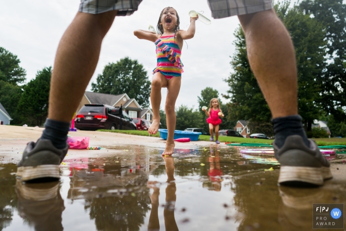 Atlanta Family photographer captures the action of a girl throwing water balloons at her dad Atlanta Family photographer captures the action of a girl throwing water balloons at her dad