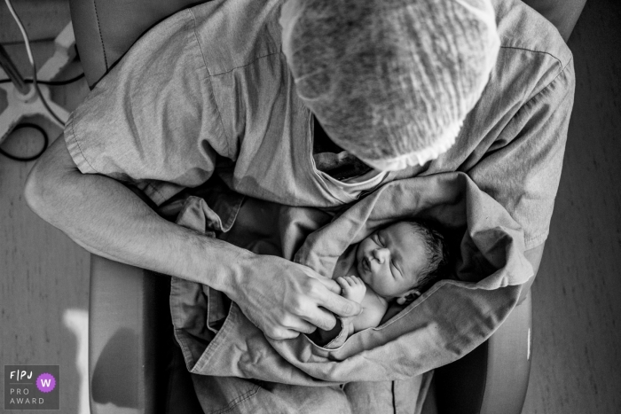 Familienfotografie in Sao Paulo im Krankenhaus Sepaco, die das Baby auf dem Schoß des Vaters dokumentiert