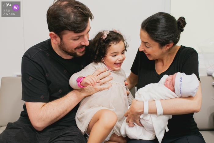 Un photographe de famille documentaire de Sao Paulo chez Pro Matre Paulista faisant une photo alors que la sœur aînée est venue rencontrer la plus jeune, et est ravie de voir sa petite sœur et ne peut contenir le sourire et le désir de l'attraper