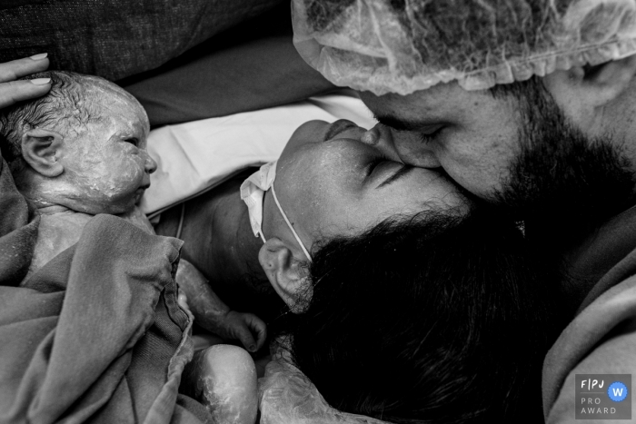 Ein dokumentarischer Geburtsfotograf aus Cuiaba, Mato Grosso, zeichnete dieses BW-Bild von Zuneigung und Emotionen mit Mama, Papa und dem neuen Baby auf