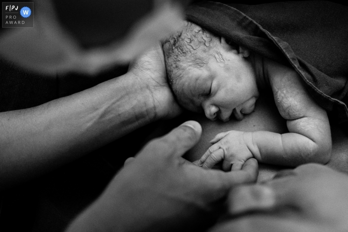 Photo by: <a href="https://www.fpja.com/documentary-family-photography-contests/thiago-braga/florianopolis/2116333">Thiago Braga - Brazil</a> A Florianpolis birth photographer at Maternidade Santa Helena captured this image of Baby minutes after birth, at the golden hour with his mother and already with his father holding hands
