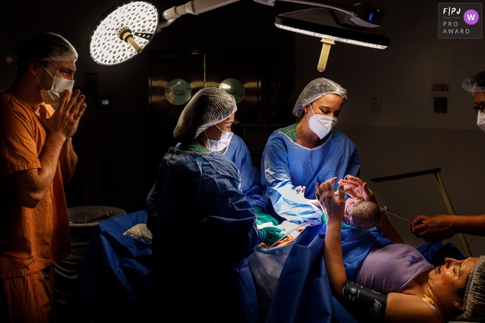 A Sao Paulo documentary birth photographer at São Luiz Itaim recorded this hospital image of baby under lights at first sight A Sao Paulo documentary birth photographer at São Luiz Itaim recorded this hospital image of baby under lights at first sight