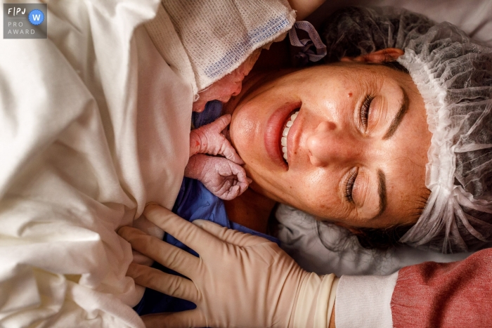 A Sao Paulo documentary birth photographer at Albert Einstein Hospital chronicled this new baby girl touching the chin of mommy