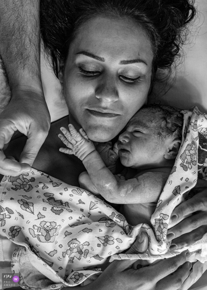 Rio de Janeiro documentary birth photography at Maternidade Perinatal Hospital showing the baby Petting mom while dad is coming to pet