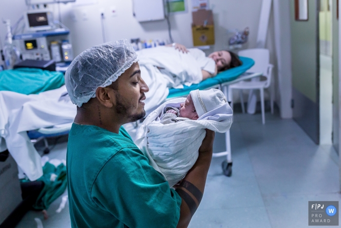 Photographie de naissance de Rio de Janeiro à l'hôpital Plantadores de Cana documentant le moment de gratitude alors que papa tient son nouveau bébé dans la salle d'accouchement de l'hôpital