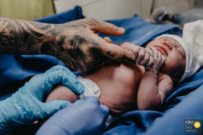 Photographie documentaire de la naissance de Santa Catarina à Maternidade Santa Helena montrant un bébé tenant le doigt de son père à l'hôpital