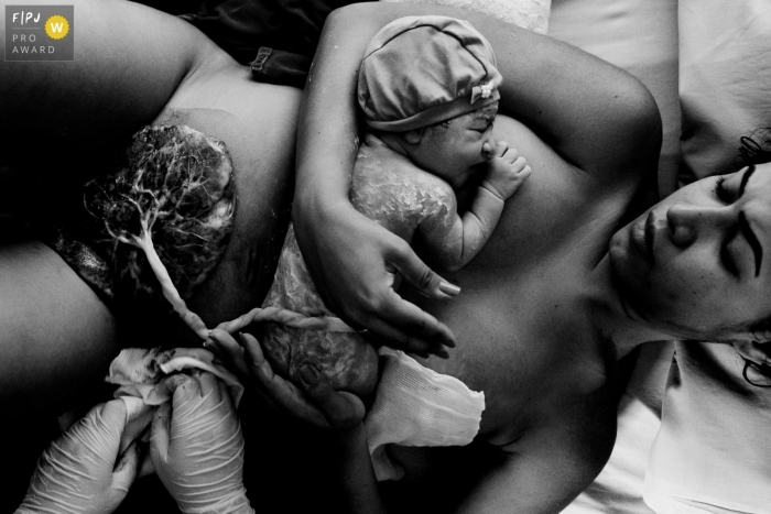 A Florianopolis, Brazil birth photographer at Maternidade Ilha captured this birth image of baby on mom in BW