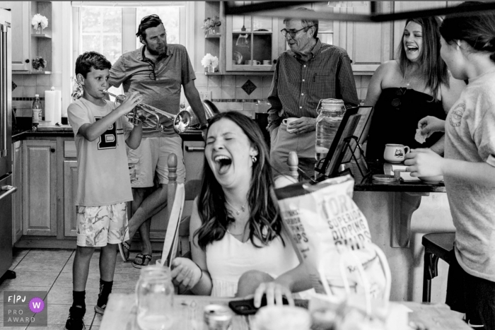 New Hampshire family photography documenting a Young boy playing trumpet for his laughing family