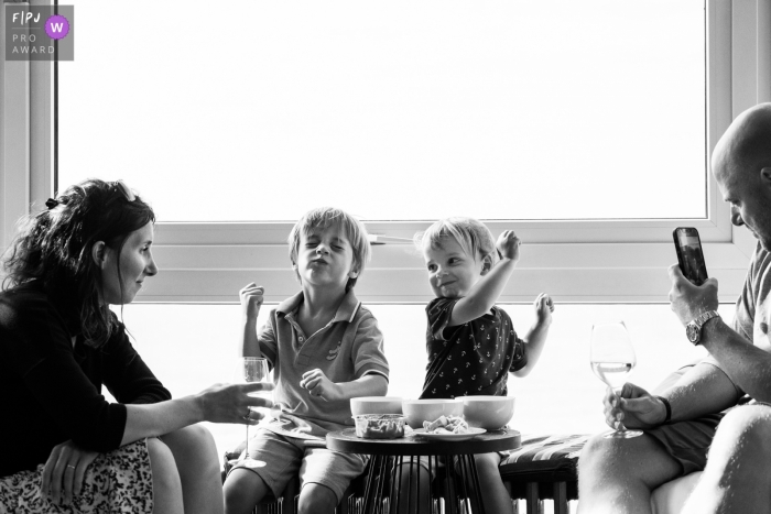 Photographie de famille documentaire anversoise de jeunes enfants assis à une table en train de manger avec maman et papa