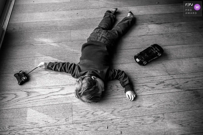 Photo by: <a href="https://www.fpja.com/documentary-family-photography-contests/emilie-marchandise/wallonie/2115316">Emilie Marchandise - Belgium</a> A Wallonie, Belgium family photographer documented an exhausted kid crashed on the wood floor with a toy car