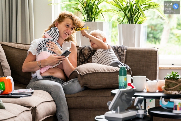 A Flevoland family photographer captured a toy helicopter stuck in moms hair, while holding a newborn