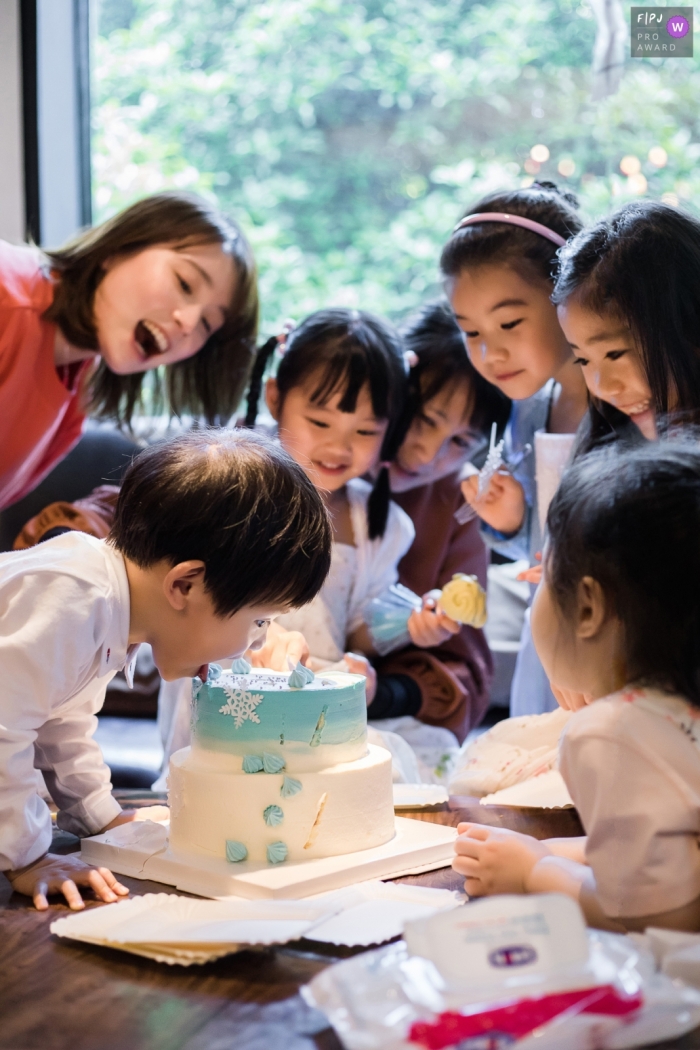 Photo by: <a href="https://www.fpja.com/documentary-family-photography-contests/mango-gu/hangzhou-city/2115707">Mango Gu - China</a> Hangzhou City, China documentary family photography showing a Boy eating cake at his birthday party surrounded by other children