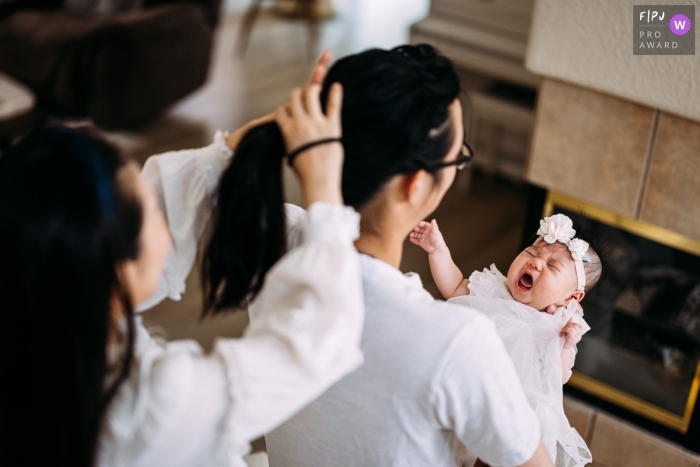 Ein Familienfotograf aus San Jose, Kalifornien, hat Mom Helps with Dads Hair festgehalten, als er ein kleines Mädchen hält