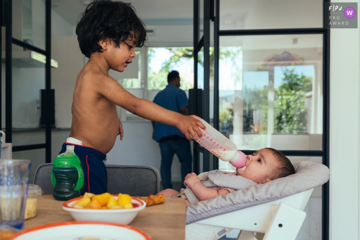 Un photographe de la famille d'Amsterdam a documenté une sœur nourrissante au biberon de Brother