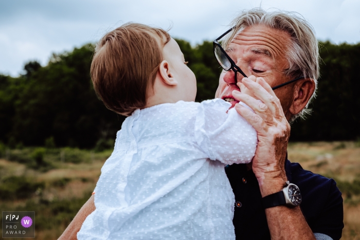 Photo by: <a href="https://www.fpja.com/documentary-family-photography-contests/jolene-den-boer/amsterdam/2115883">Jolene den Boer - Netherlands</a> Amsterdam family photography documenting Granddaughter reaching for grandpas glasses