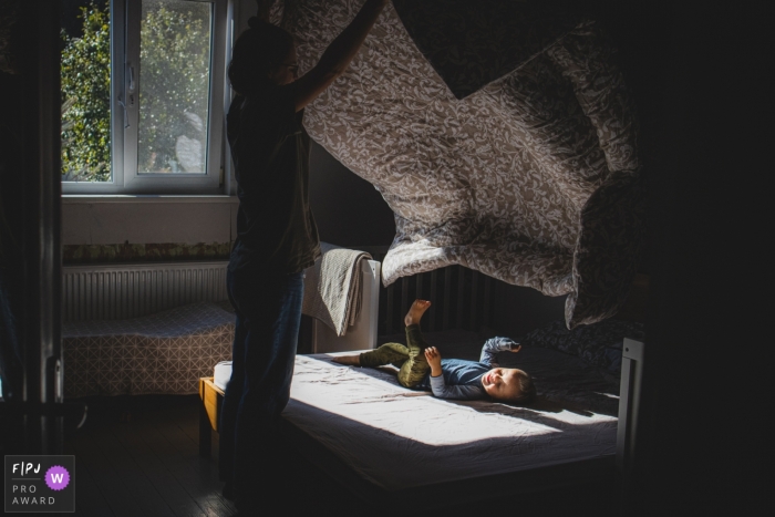 Dokumentarische Familienfotografie aus Litauen, die Kinder aufzeichnet, die morgens im Schlafzimmer spielen