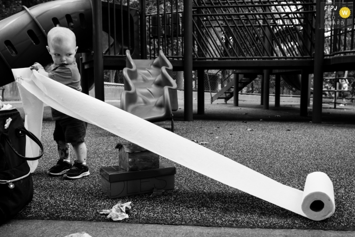 An Atlanta, GA family photographer documented a Young boy unrolling paper towels at a park as he tries to clean up