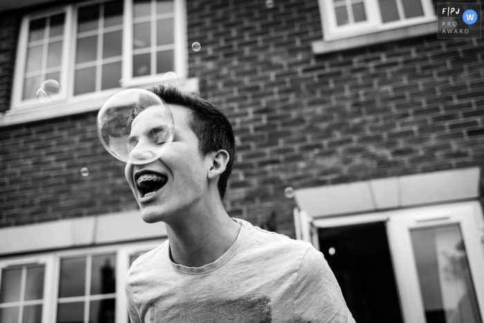Photo by: <a href="https://www.fpja.com/documentary-family-photography-contests/alice-chapman/cambridgeshire/2116100">Alice Chapman - United Kingdom</a> A Cambridgeshire, UK family photographer documented A teenage boy with braces laughing at a bubble in the garden