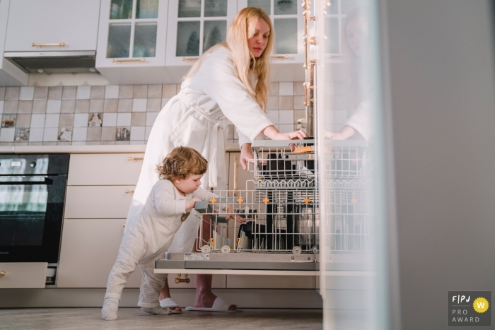 A Dubai documentary family photographer recorded a Mom and her kid making up the kitchen dishes in the dishwasher A Dubai documentary family photographer recorded a Mom and her kid making up the kitchen dishes in the dishwasher