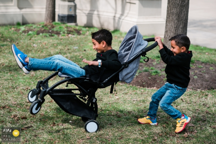 Un photographe de famille documentaire de Chicago a capturé cette séance de hijinks de poussette avec des frères à l'extérieur sur l'herbe